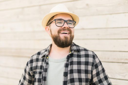Laughing attractive man wearing hat over wooden background - emotion and vacation travel holidays concept