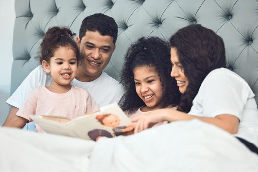 Smiling like he hit the lottery. Shot of a beautiful young family talking and bonding in bed together.