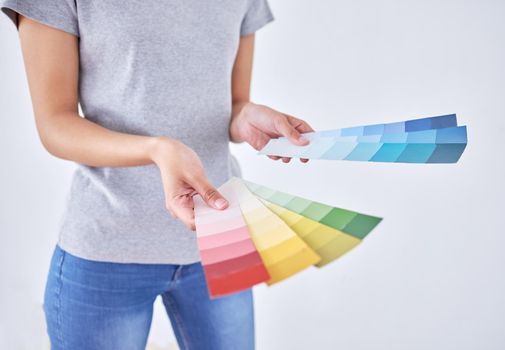 I just cant pick one. Shot of an unrecognizable woman holding color swatches while standing against a white background.