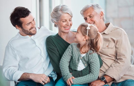 Adorable little girl looking at her grandmother while sitting together with family. Happy child sitting with her father and grandparents at home. Caucasian family smiling while spending time together
