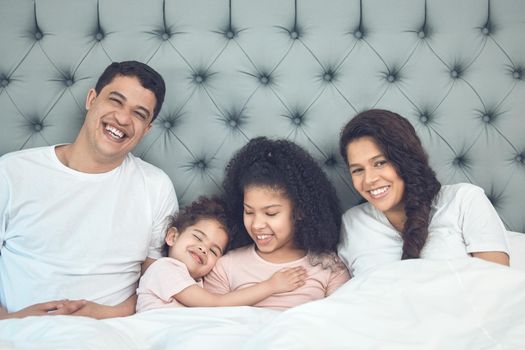 Blissful mornings. Shot of a beautiful young family talking and bonding in bed together.