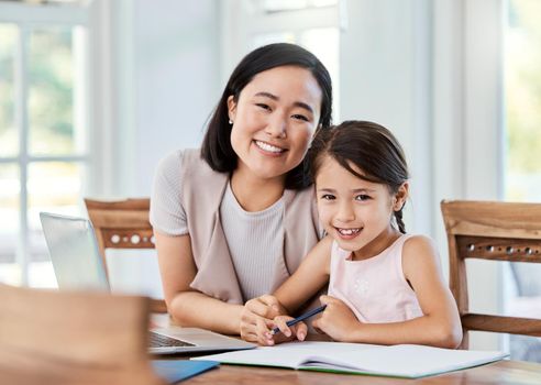 Being part of a family means smiling for photos. Shot of a young mother helping her daughter with her homework at home.