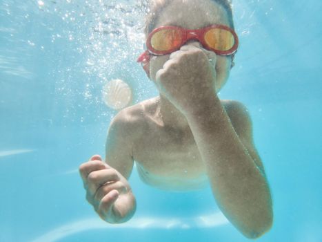 Submerged in summer. Shot of an adorable little boy wearing goggles while swimming underwater.