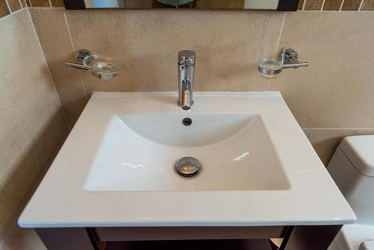 Washbasin in the bathroom, beige with chrome accessories. Modern repair.