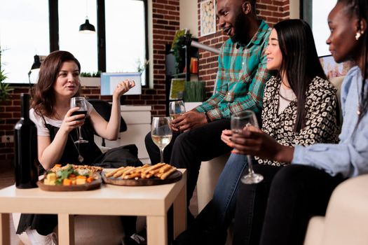 Multiracial group of friends having wine party while talking