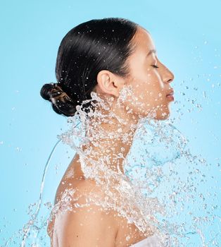 Life happens, showers help. Shot of a beautiful young woman being splashed with water against a blue background.