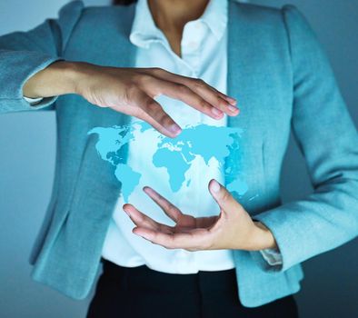 Focused on growth. Cropped shot of an unrecognisable businesswoman standing alone in the office and holding a cgi globe.