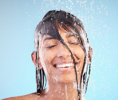 Embrace your inner child. Shot of a young woman washing her hair in the shower against a blue background.