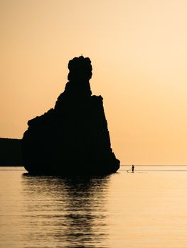 Silhouette of a man floating on a supboard at sunset in Ibiza