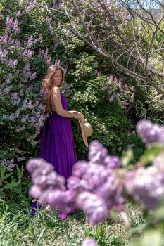 Fashion Model in Lilac Flowers, Young Woman in Beautiful Long Dress Waving on Wind, Outdoor Beauty Portrait in Blooming Garden