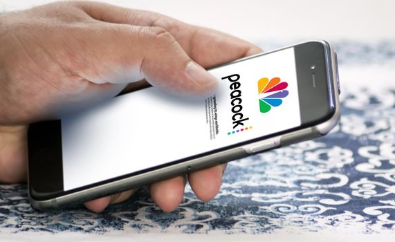 New York, USA, May 2022:A hand holding a phone with the Peacock Tv mobile app on the screen