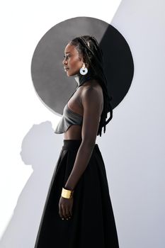 Fierce and fabulous. Shot of an attractive young woman posing in a black outfit against a wall with a circle on it.