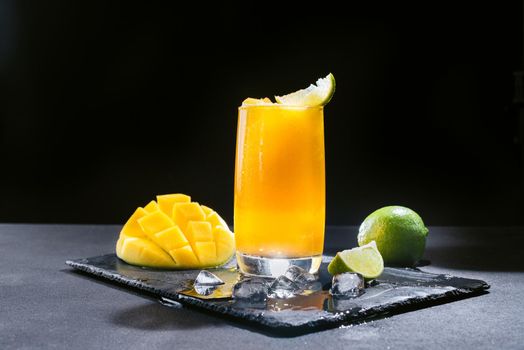 A Mexican smoothie drink made from mango, chili peppers, salt, and lime. A refreshing summer smoothie on a black background of bright orange.