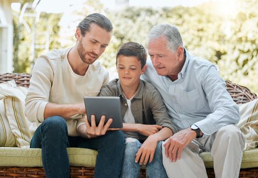Lets check what the score is. Shot of a man using a digital tablet while sitting outside with son and his elderly father.