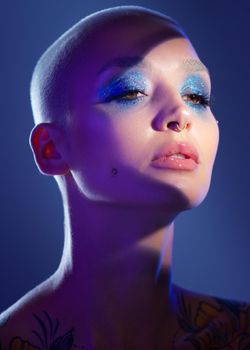 Im not a woman who likes to stay in the shadows. Studio shot of an attractive young woman wearing edgy makeup against a blue background.