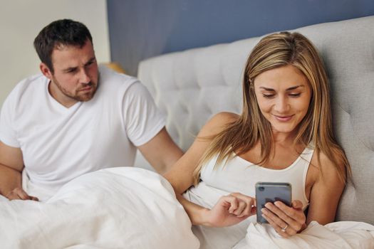 My mom was right about her. Shot of a husband catching his wife texting with someone else in bed.