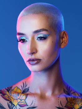 Edgy but beautiful. Studio shot of an attractive young woman wearing edgy makeup against a blue background.