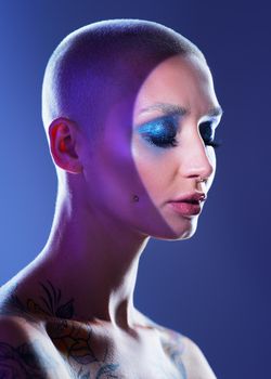 Sophisticated with a hint of sass. Studio shot of an attractive young woman wearing edgy makeup against a blue background.