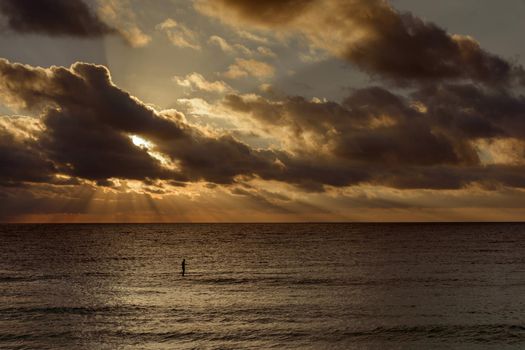 Silhouette of a man on a surf in the sea at dawn.