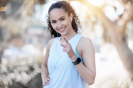 Keep yourself accountable. a sporty young woman wearing earphones and pointing at the camera.