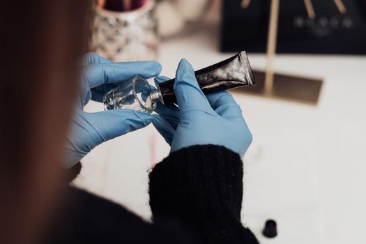Close Up of Make-Up Artist in Gloves Squeezes a Tube of Paste Into a Vessel