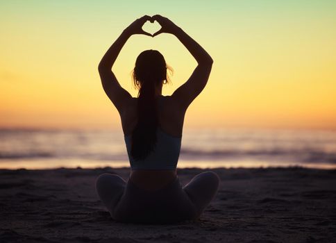 Start catching feelings with positivity. a unrecognizable female doing yoga at the beach.