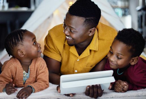 You know its a good tablet if its dad approved. an adorable little boy and girl using a digital tablet with their father during bedtime at home.
