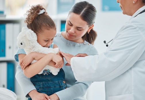 Encourage your child to stay calm during their routine shots. a little girl getting an injection from a doctor in a clinic.