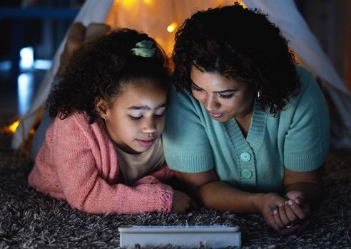 A fairytale for the digital age. an adorable little girl using a digital tablet with her mother during bedtime at home.