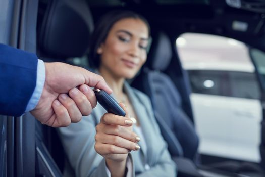 Why dont you fire her up. Closeup shot of an unrecognizable male car salesman handing a key to an attractive female client.