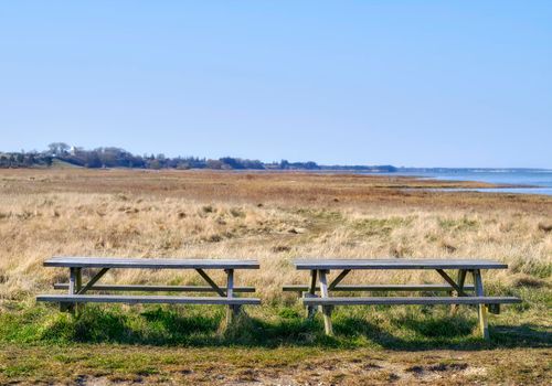 Two wooden benches on a field overlooking the ocean. A quiet place to enjoy nature and the peace it has to offer. Find tranquility amongst the green grass and views of the ocean. Beauty in nature