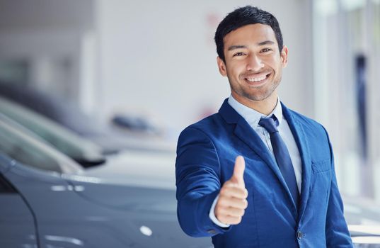 Your finance has been approved. Cropped portrait of a handsome young male car salesman giving thumbs up while working on the showroom floor.