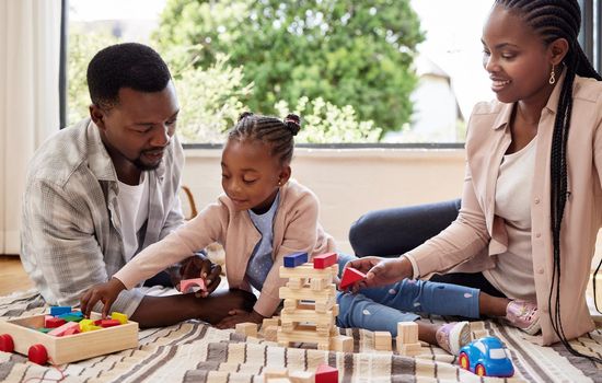 An architect in the making. a little girl playing with blocks with her parents at home.