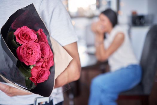 Its the small things that matter. an unrecognizable man surprising his girlfriend with flowers at home.