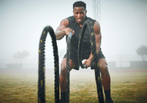 The real battle is within yourself. Portrait of a muscular young man exercising with battle ropes outdoors.