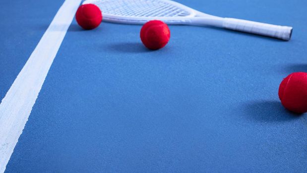 Its tennis time. multiple tennis balls lying on a blue tennis court.