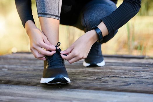 I have goals to chase after. Closeup shot of an unrecognisable woman tying her laces while exercising outdoors.