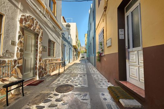 Scenic street view of old historic houses, residential buildings, traditional infrastructure in cobblestone alleyway road. Tourism abroad, overseas travel destination in Santa Cruz de La Palma, Spain