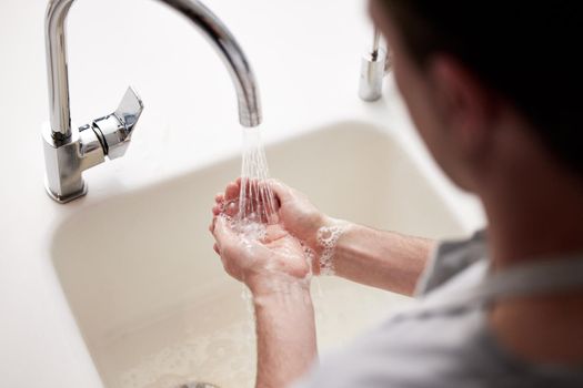 Always wash your hands carefully. an unrecognizable person washing their hands in a kitchen sink at home.