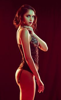 Sultry goddess. Cropped portrait of a beautiful young woman posing in lingerie against a red background.