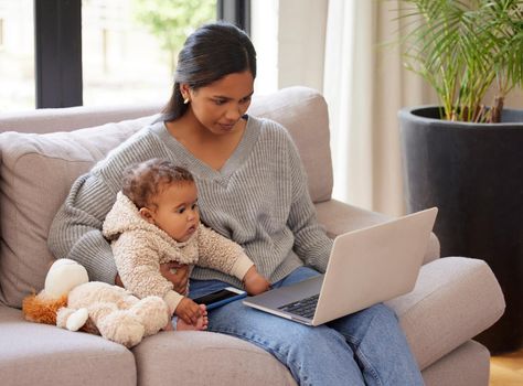 My content is all about my motherhood journey. a young woman working on her laptop while sitting in the lounge with her baby.