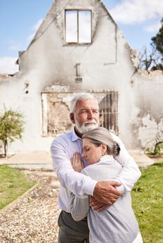 Losing your home is like losing a piece of your heart. a senior couple comforting each other after losing their home to a fire.
