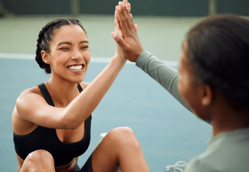 You killed that. two attractive young female athletes high fiving while exercising outside on a sports court.