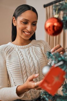 Its beginning to look a lot like Christmas. a young woman decorating a Christmas tree at home.
