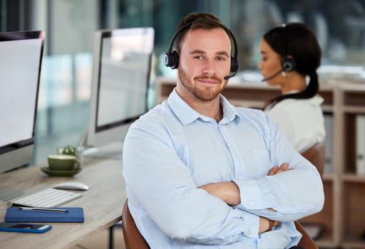 Everything has a solution and well find it. Portrait of a confident young man using a headset in a modern office with his colleague working in the background.