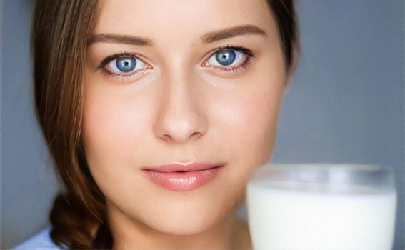 Happy young woman with glass of milk or protein cocktail, healthy drink, diet and wellness