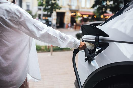 Human hand is holding Electric Car Charging nozzle.