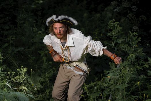 Sea robber ship captain armed pirate goes through jungle. Concept historical halloween. Filibuster cosplay