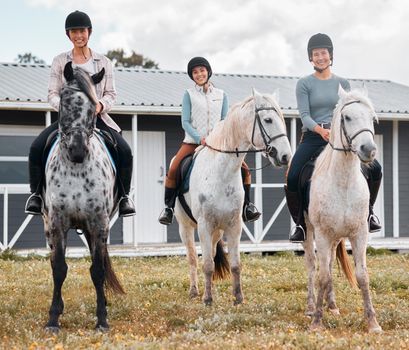 On horseback. Full length portrait of three attractive young women horse riding on a farm.