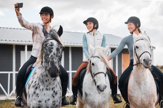 Smile, ladies. three attractive young women taking selfies while horse riding on a farm.